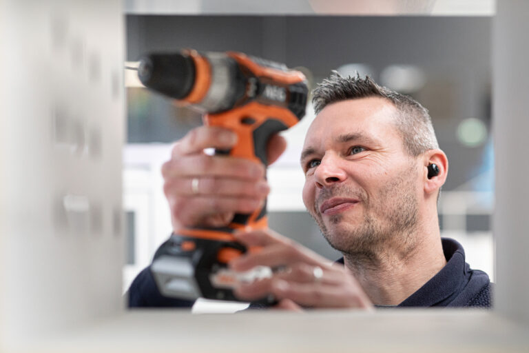 Technicien Automat-e en train de visser la structure du distributeur automatique