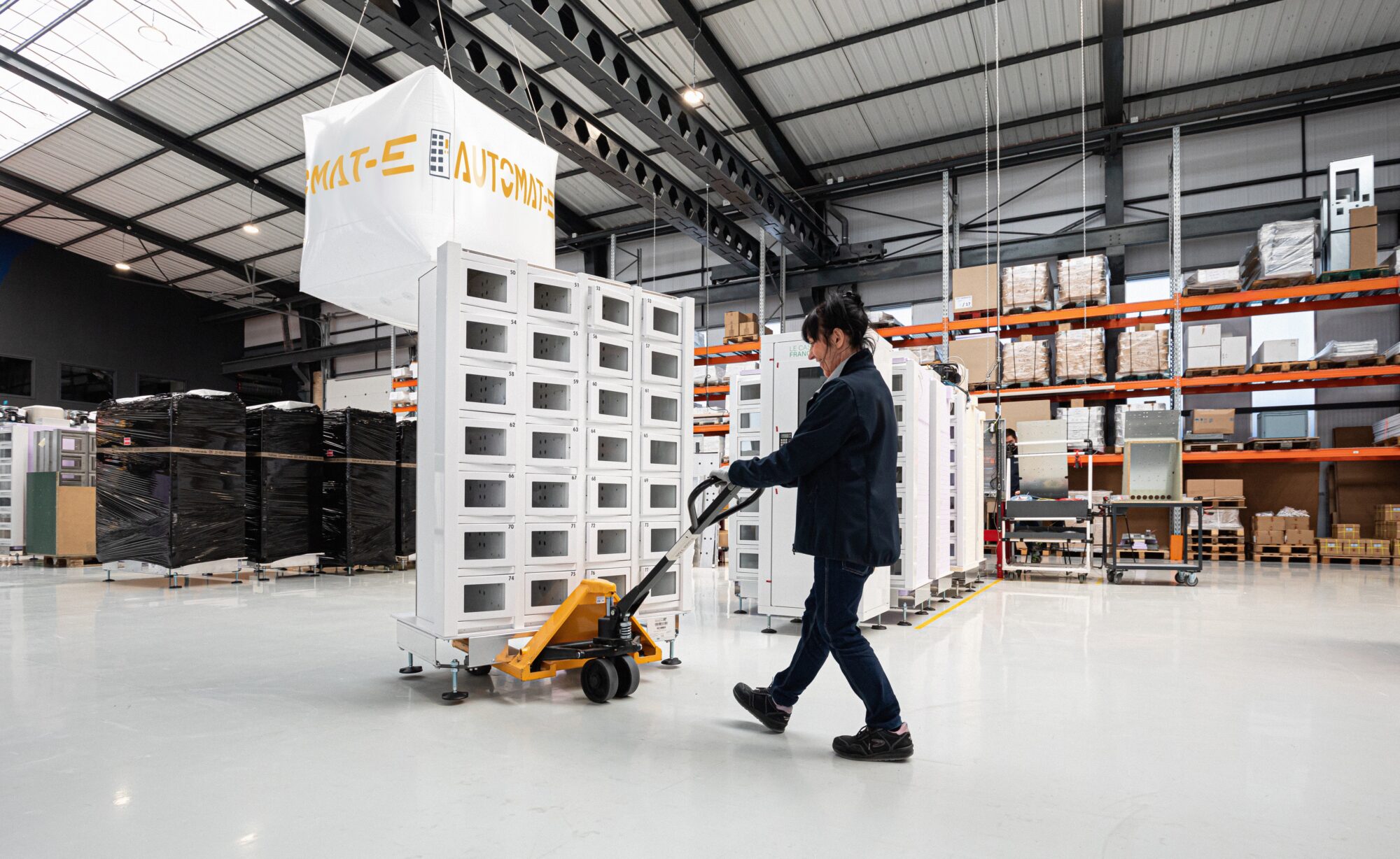 Opératrice d'assemblage transportant une machine distributruce dans l'usine